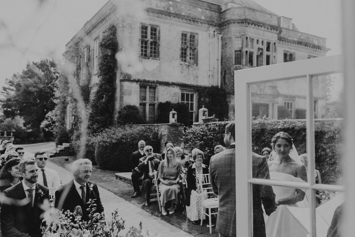 Black and white vintage photo of wedding guests outside historic building.