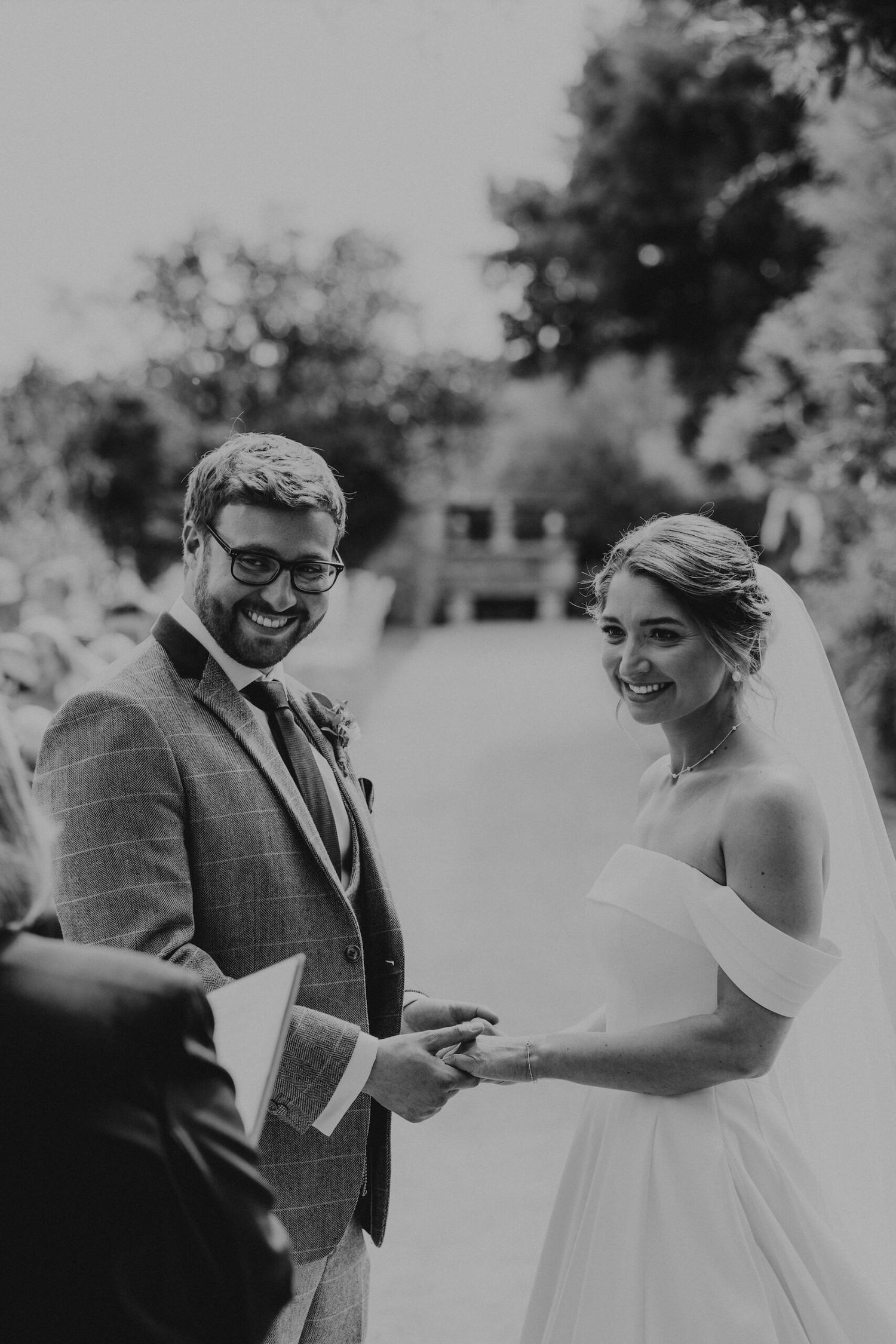 Black and white wedding ceremony photo during ring exchange.