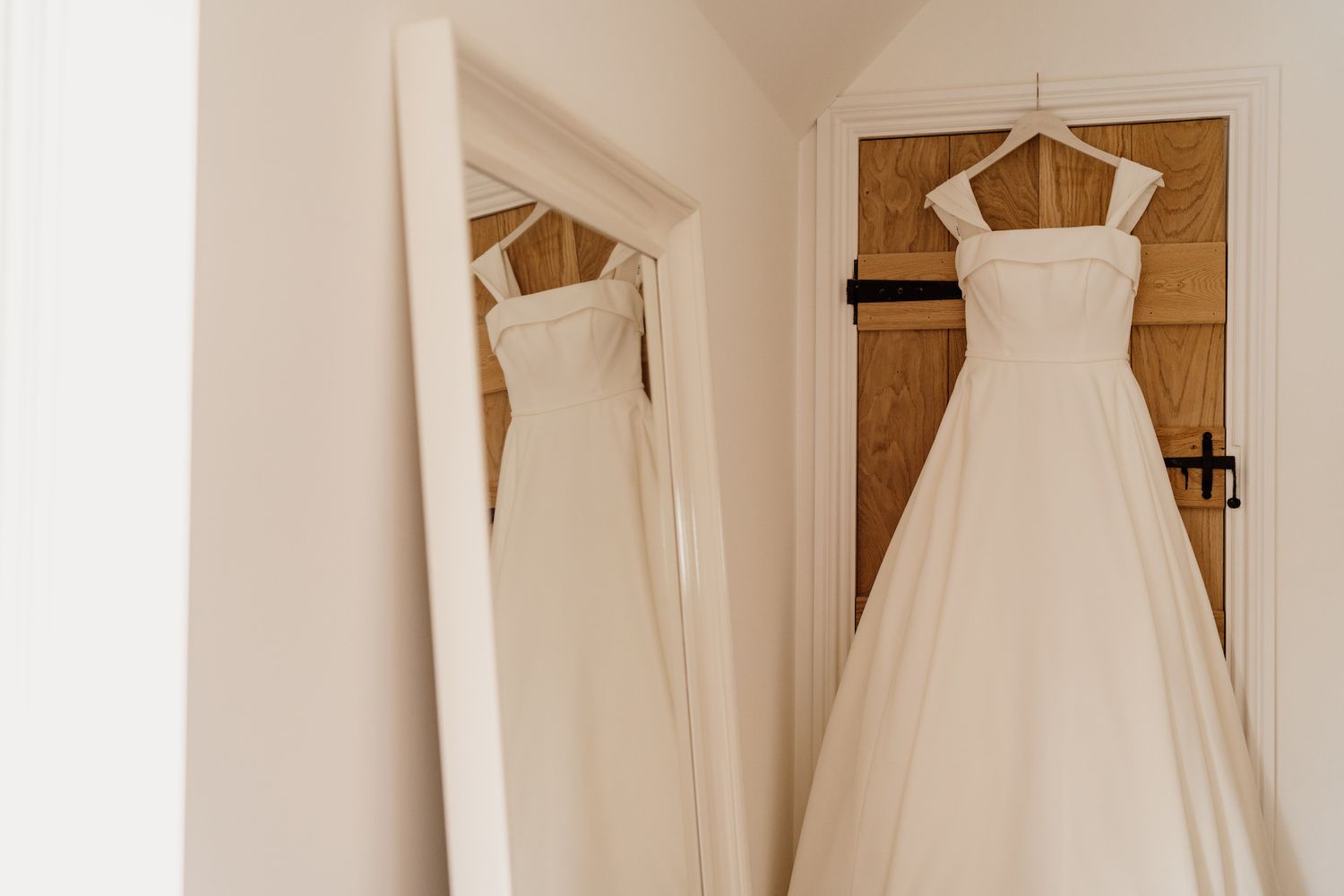 Collection of elegant white wedding dresses hanging on display against wooden walls.
