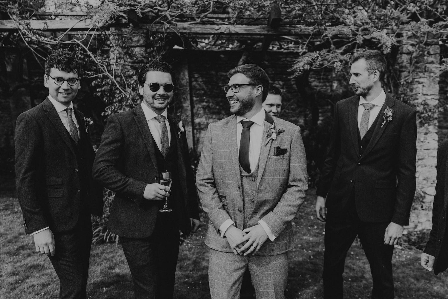Wedding party gathered outdoors for group photos in black and white.