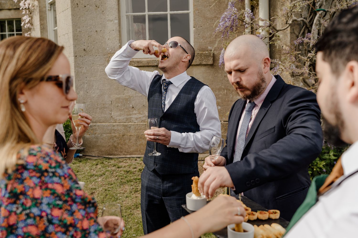 Wedding guests enjoying drinks and appetizers during an outdoor garden reception.