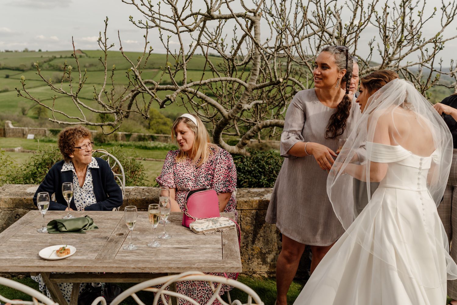 Wedding celebration at an outdoor rustic table with guests enjoying a casual meal.