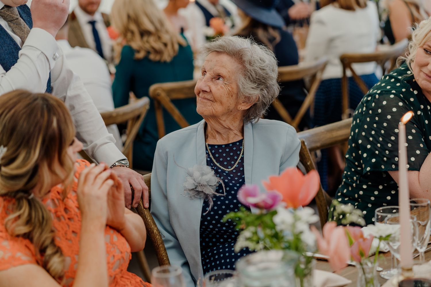 Wedding reception guests engage in lively conversation at elegant table settings.