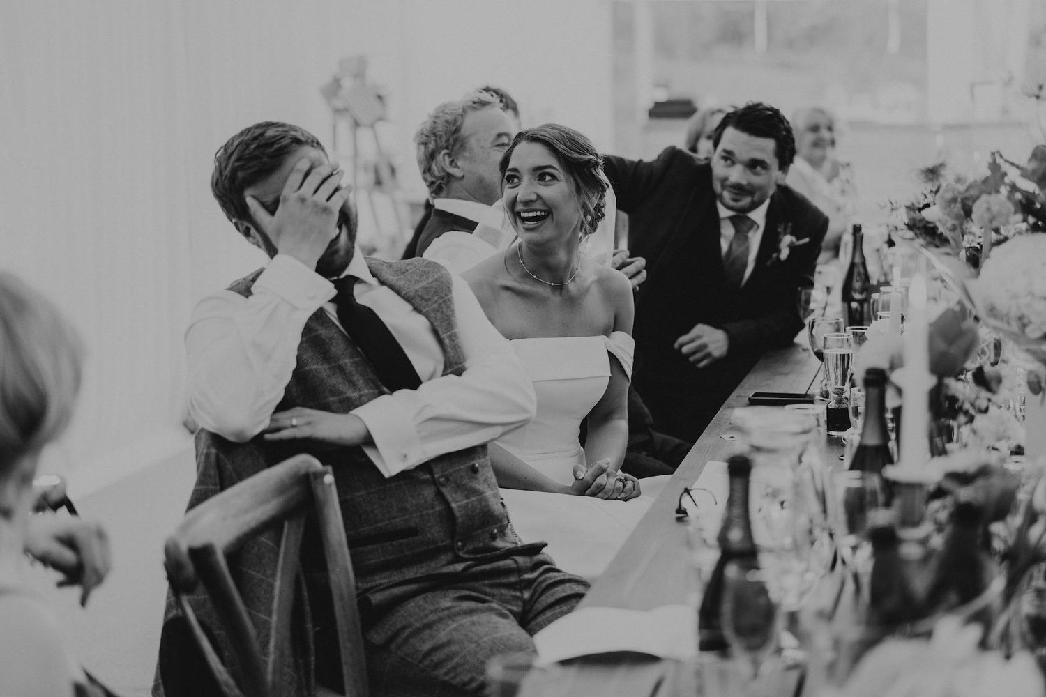 Wedding reception guests celebrate and dance together in a white tent during an evening party.