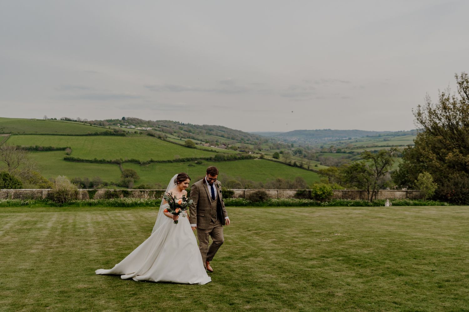 Panoramic view of a wedding ceremony setup on a hillside with sweeping countryside views.