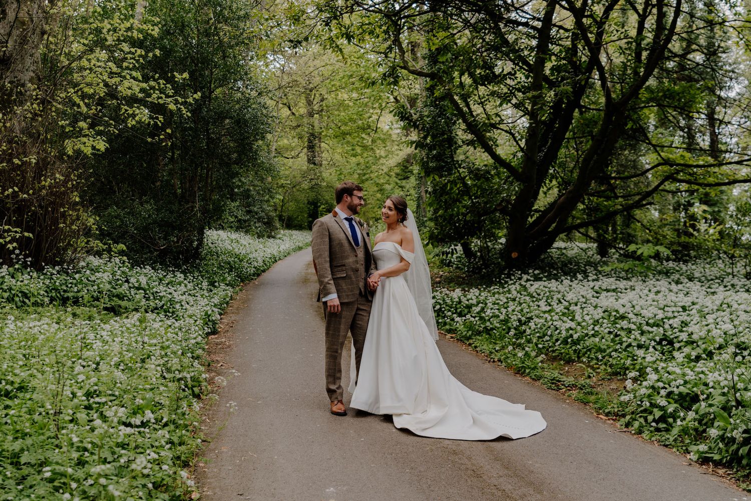 Couple strolls along a spring garden path surrounded by blooming white flowers.
