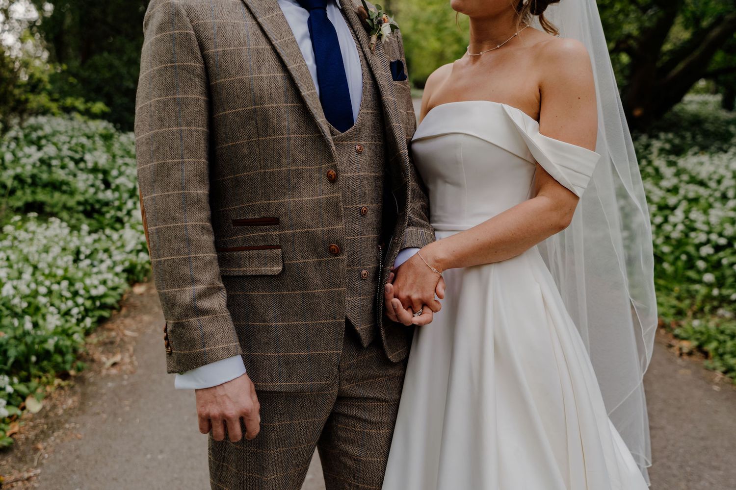 Close-up view of couple holding hands during their countryside wedding photoshoot.