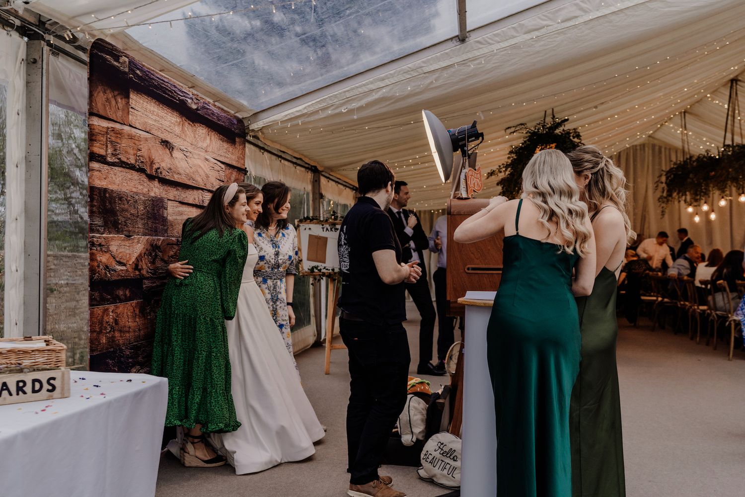 Wedding guests mingle under a white tent during the reception celebration.