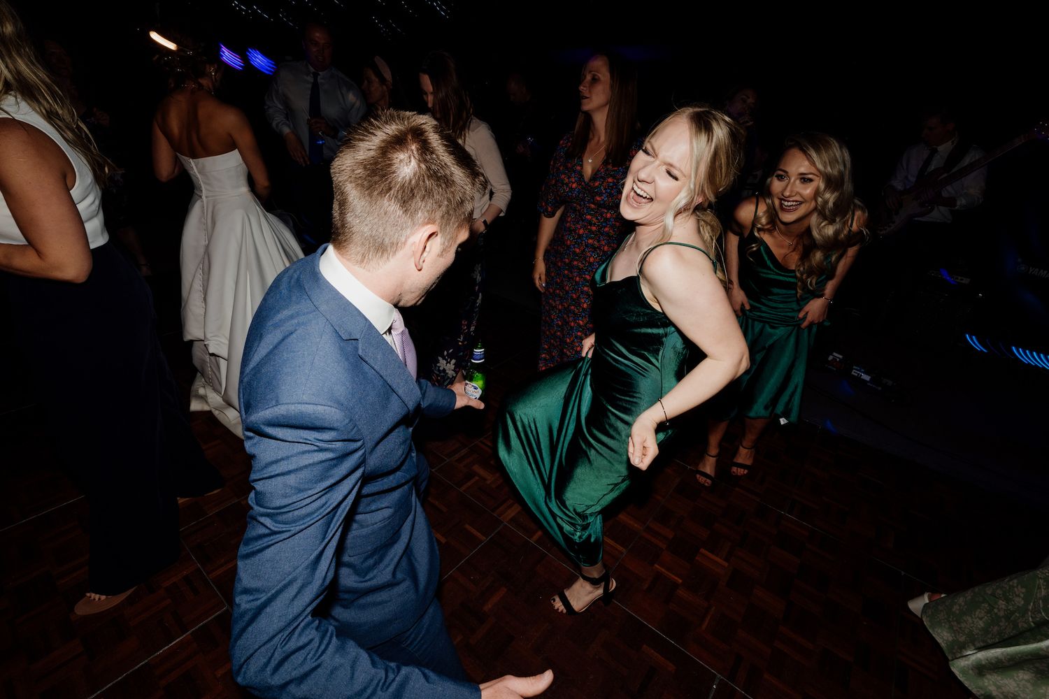Guests dancing energetically on a dark reception dance floor.