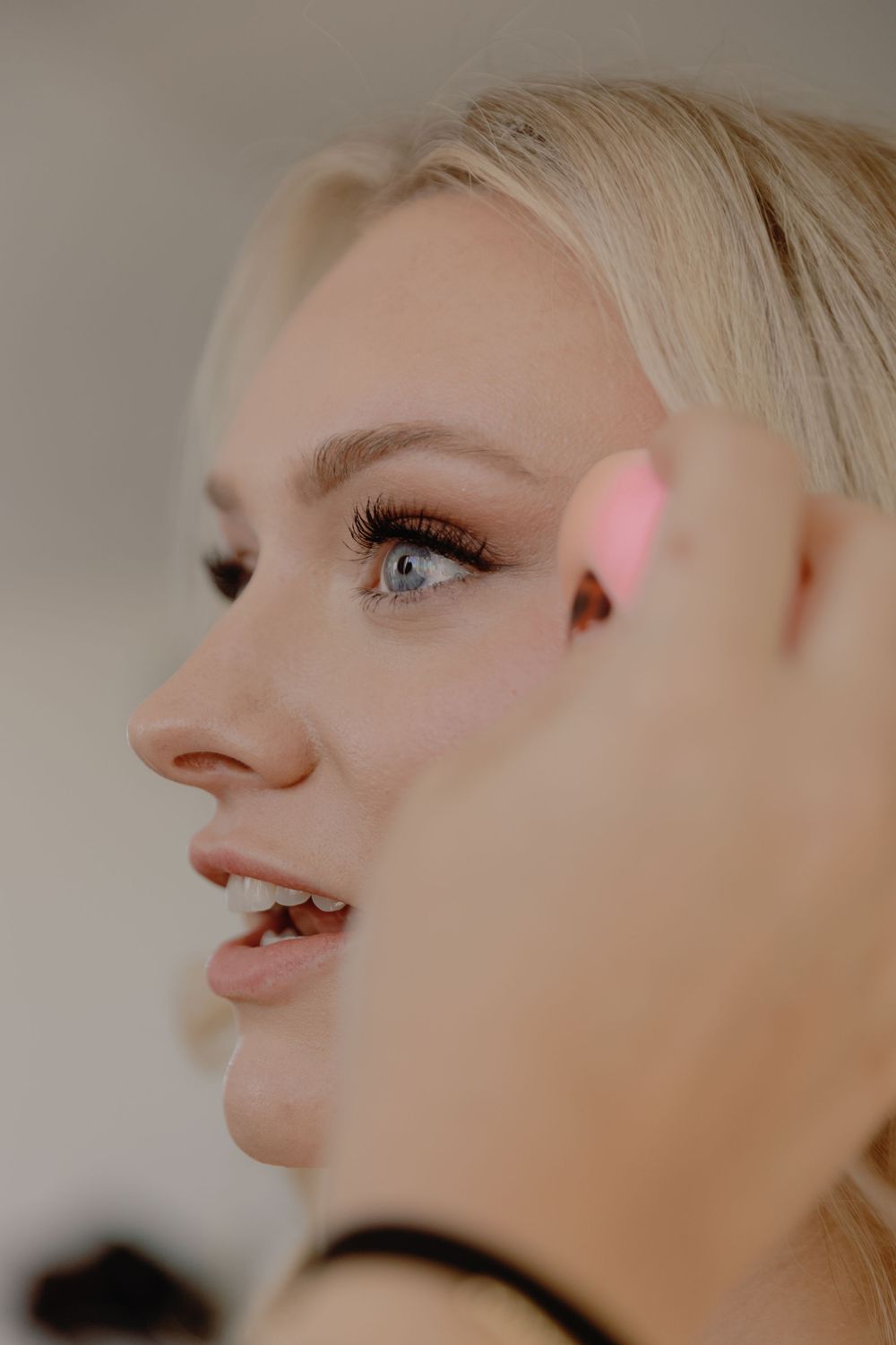 Close-up profile portraits against neutral background showcasing delicate makeup and blonde hair styling.