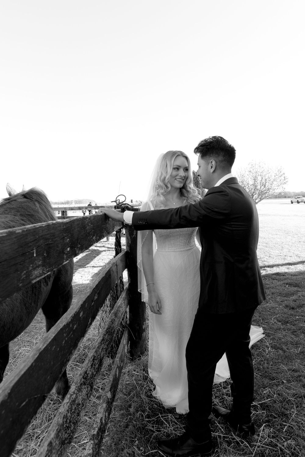 A pair in formal attire pose against a wooden fence in a black and white candid photo sequence.