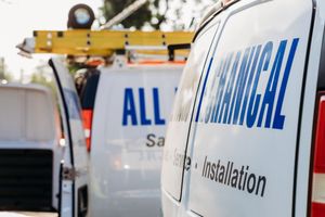 Close-up view of service van with electrical installation branding, with ladder and equipment visible in background.