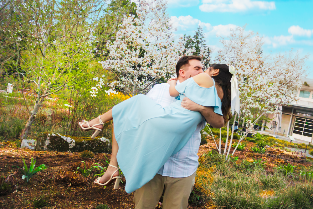 A romantic spring moment captured in front of blooming cherry blossom trees on a sunny day.