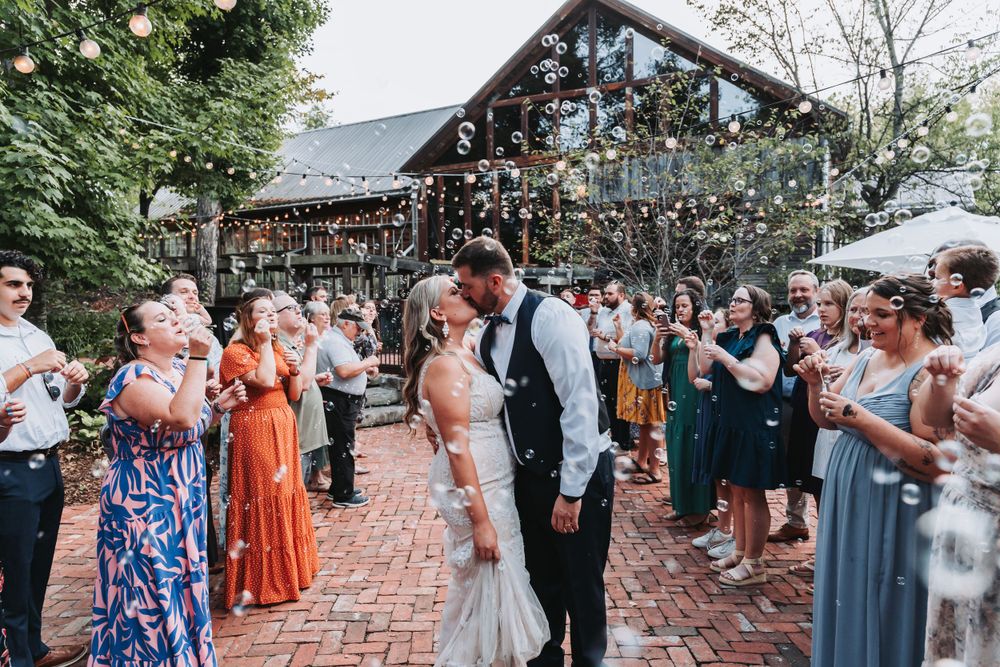Joyous celebration during a wedding ceremony at a rustic log cabin venue with string lights and brick pathway.