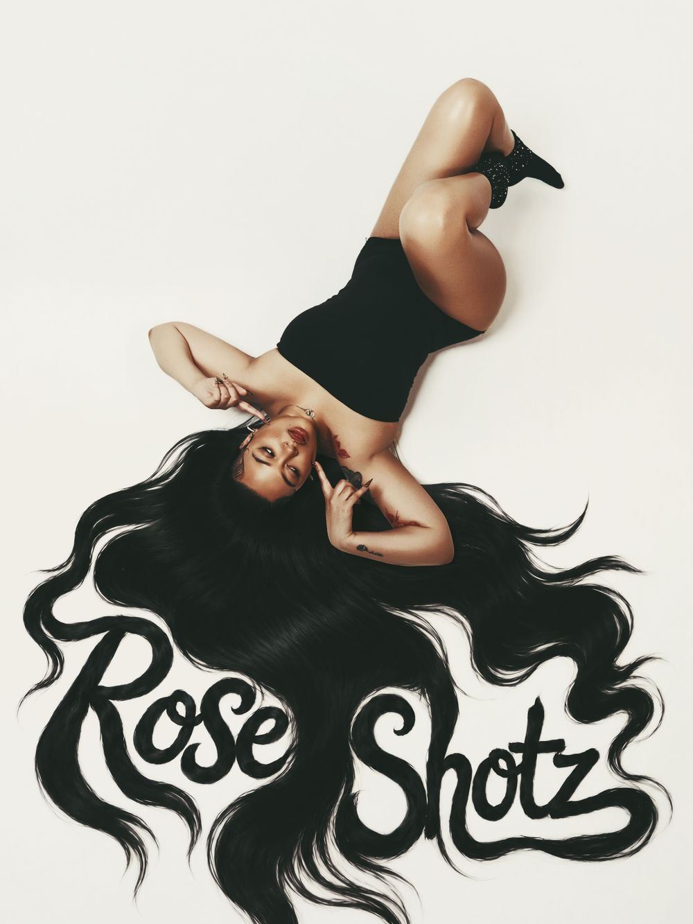 Woman in black outfit lying down with long flowing hair forming Rose Shotz logo text on white background.