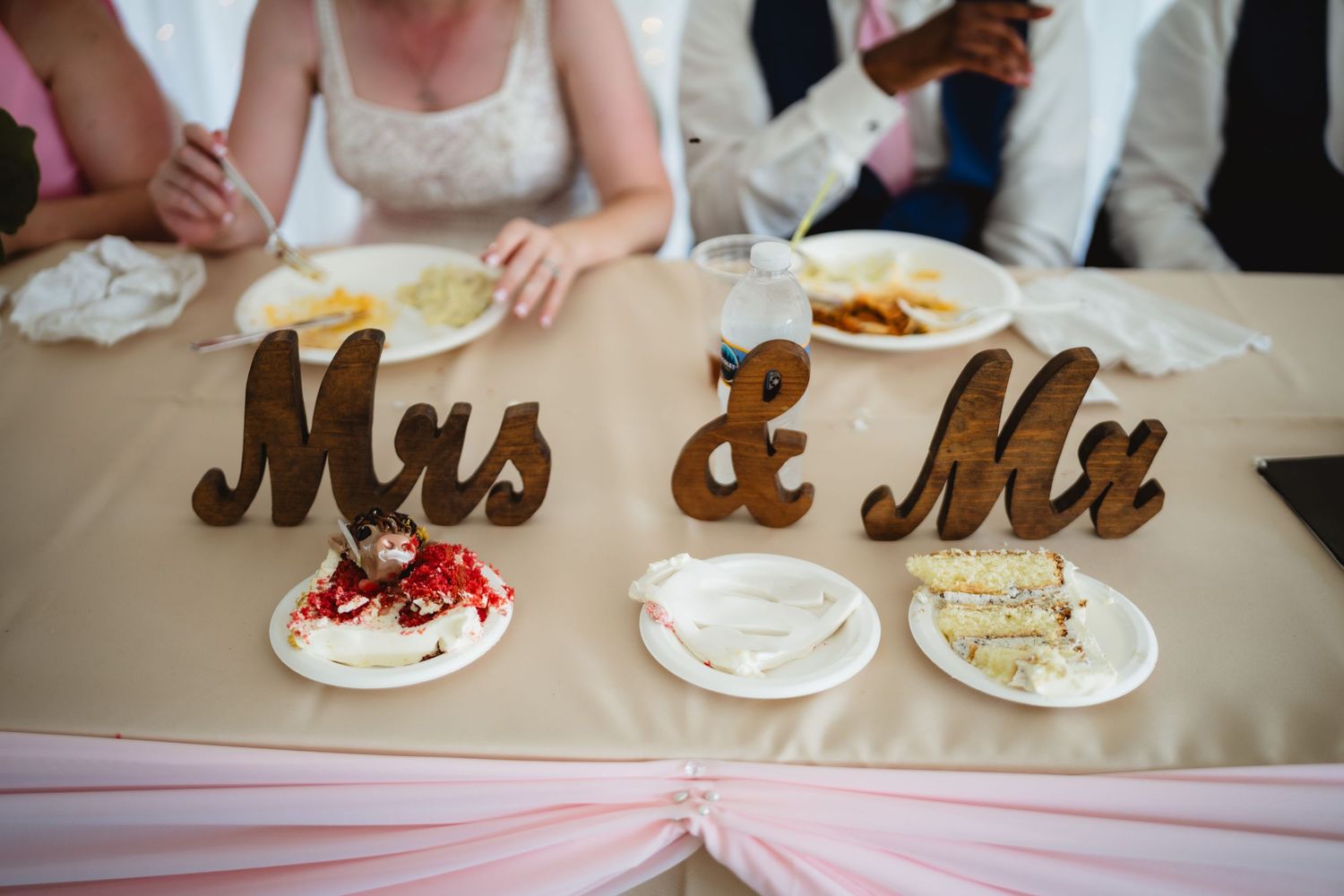 Wedding party sits at long table for dinner reception with wooden Mr and Mrs letters as rustic decor.