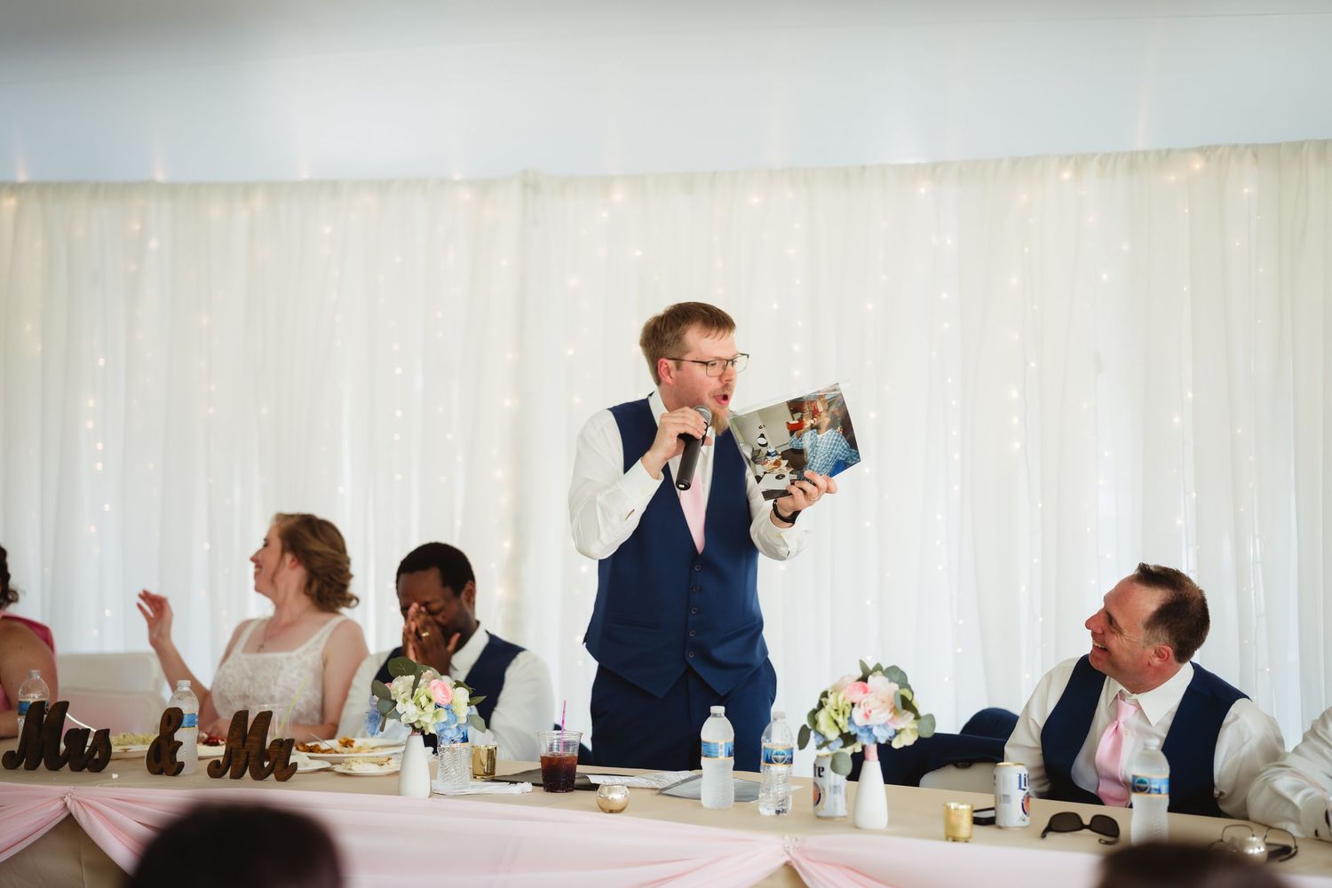 Wide panoramic collage of candid moments during a wedding reception in a white tent with elegant table settings.