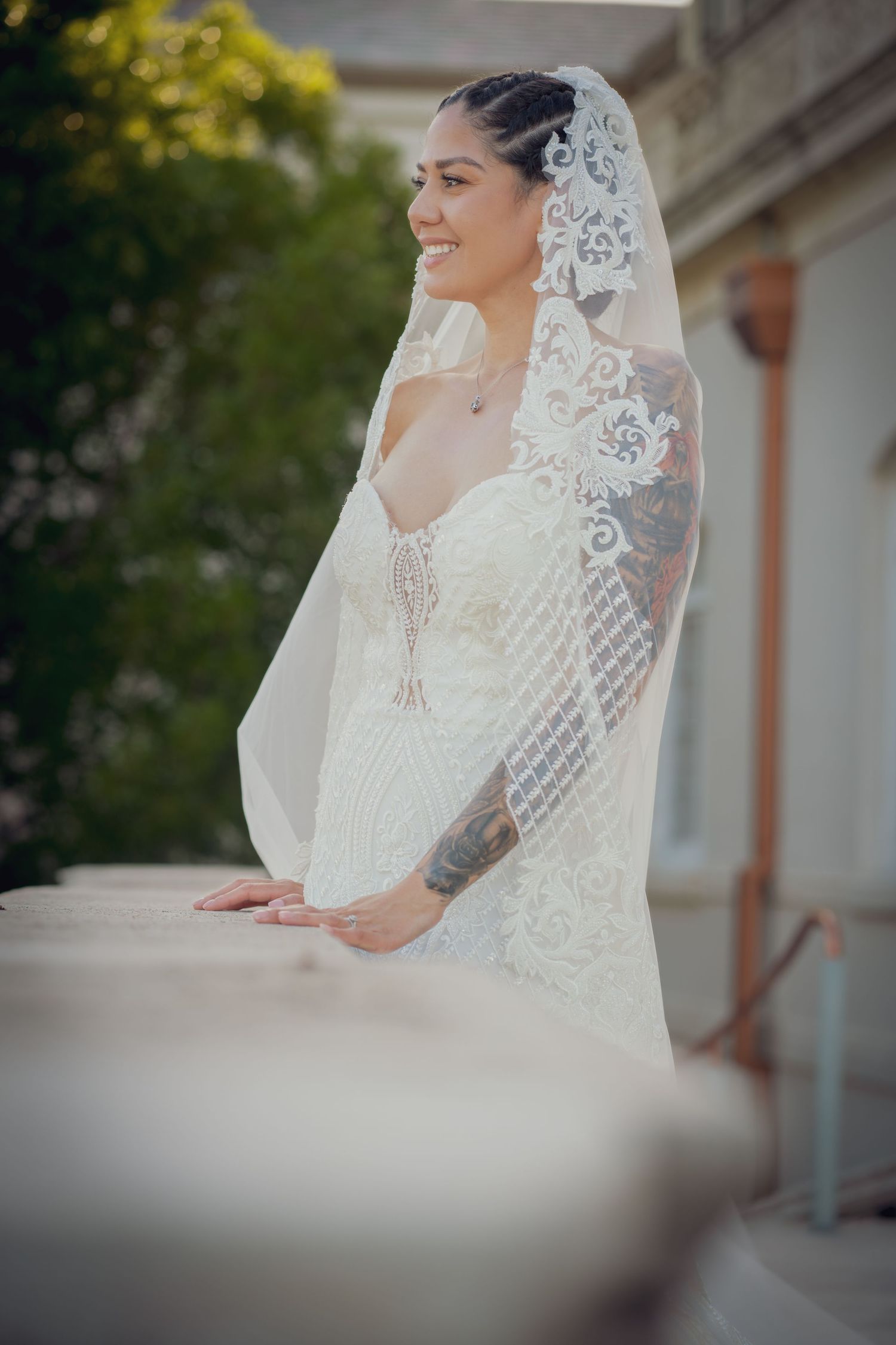 Beautiful bridal portrait featuring an elegant white lace wedding dress with a detailed veil in soft natural lighting.