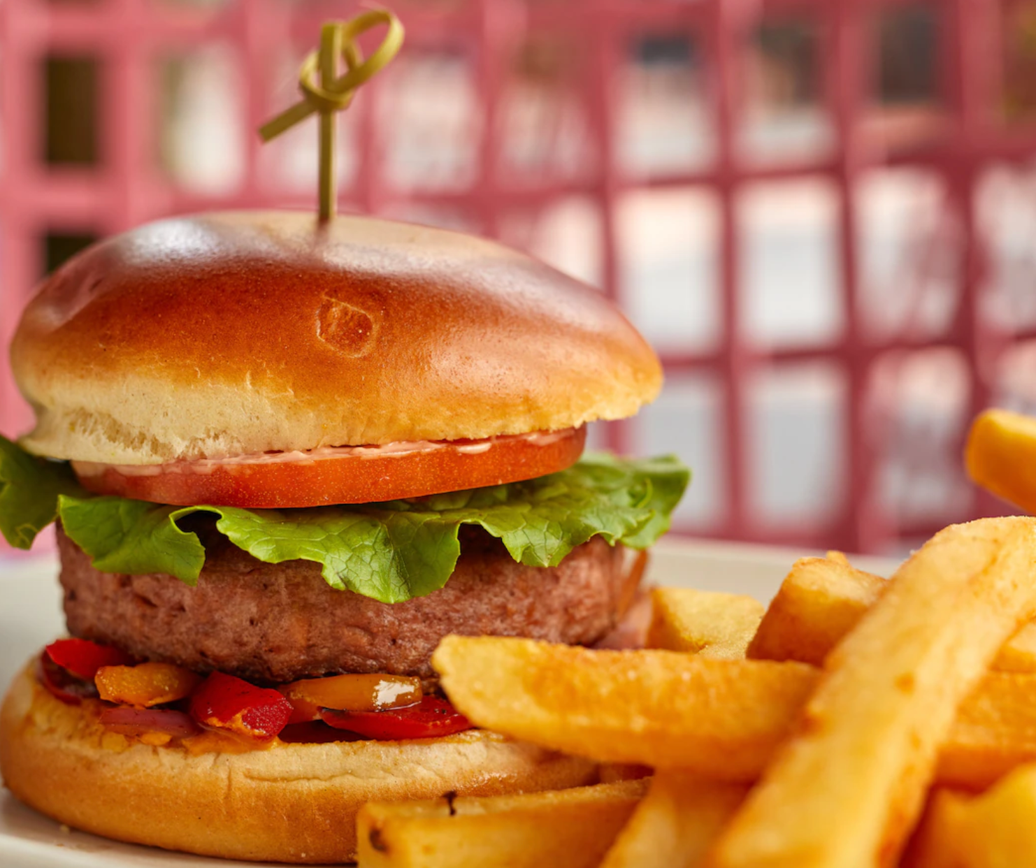 Juicy hamburger with lettuce and tomato served with golden french fries on the side.