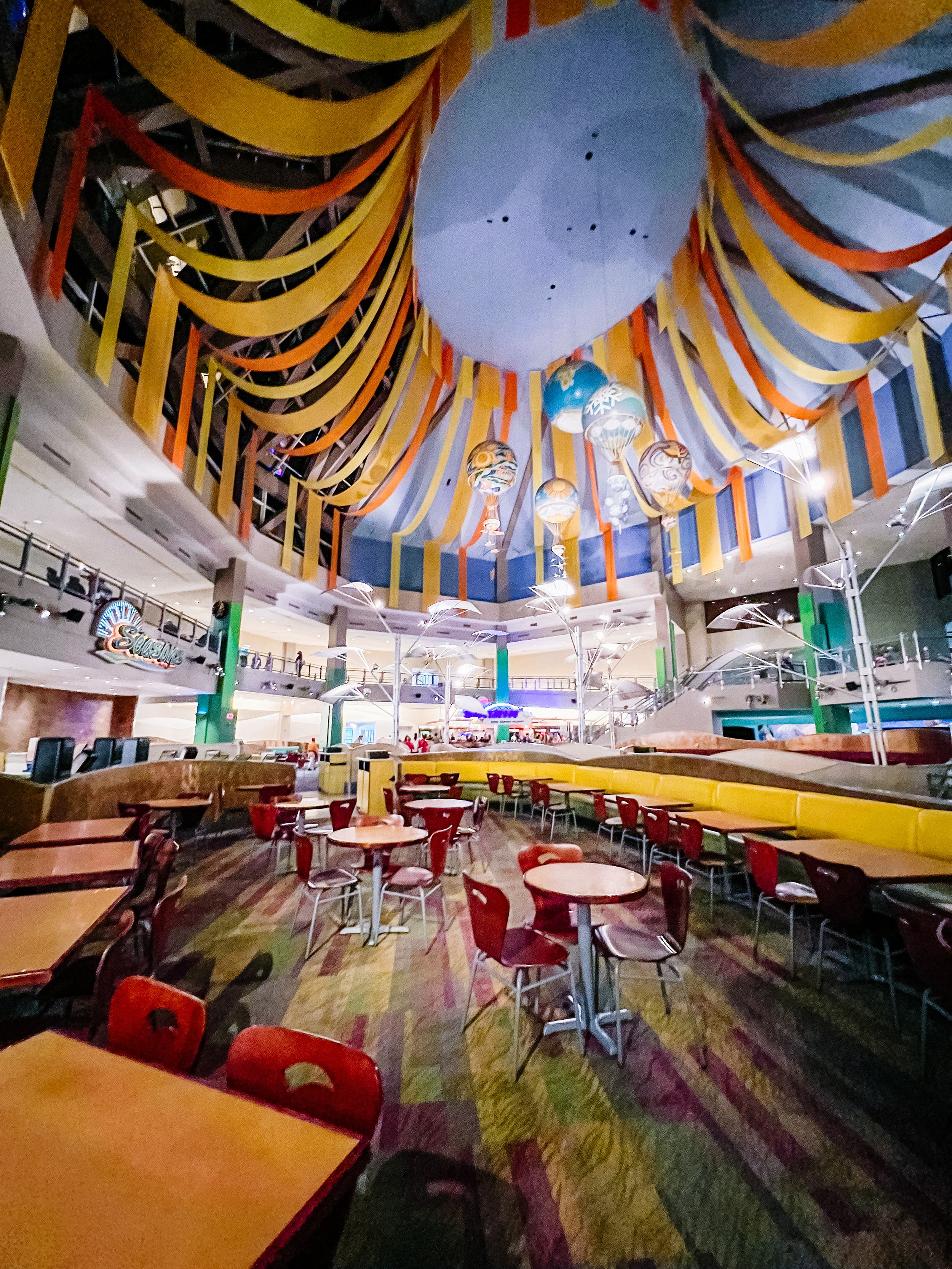 Colorful cafeteria interior with striped ceiling decorations and round tables.
