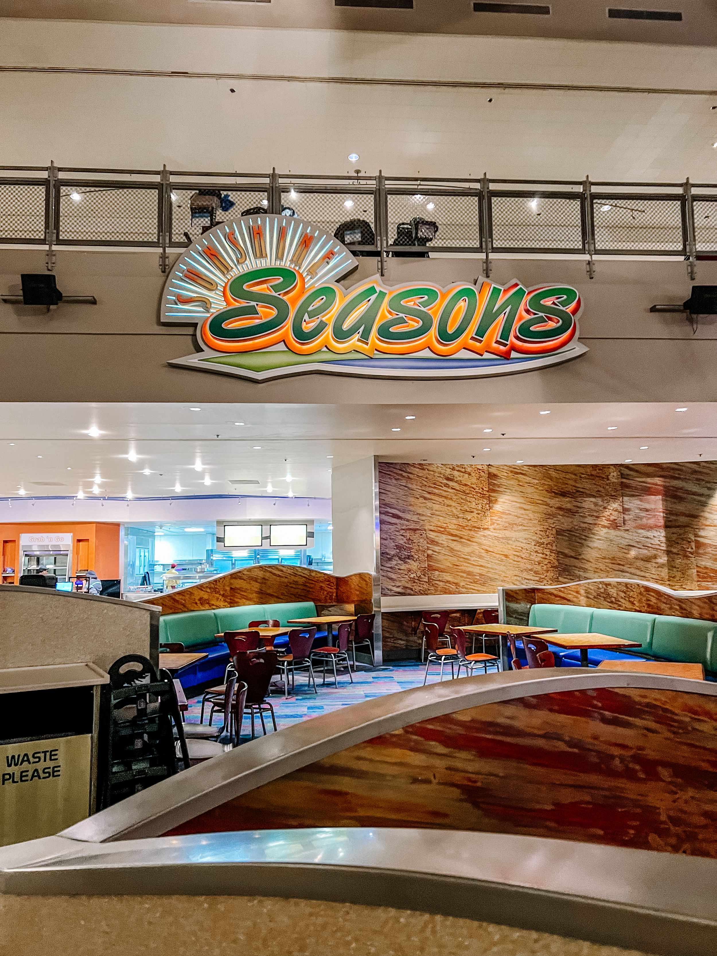 Seasons dining area with retro neon sign and curved seating arrangements.