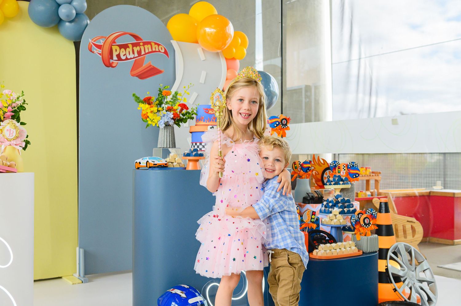 A child in pink dress celebrates a birthday with balloons, presents and party decorations in a festive room.