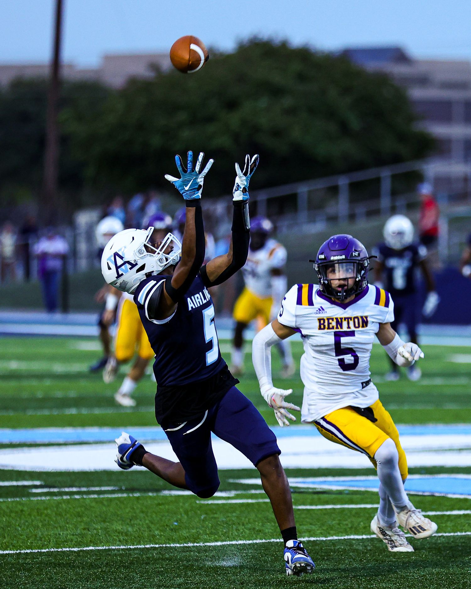 Football player diving to catch a ball while another player defends during an intense game moment.