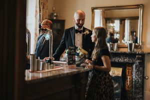 Wedding guests stand at the bar at Cleatham Hall.