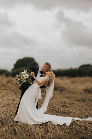 A bride in a flowing white dress lays dances with her groom in a field near Cleatham Hall.