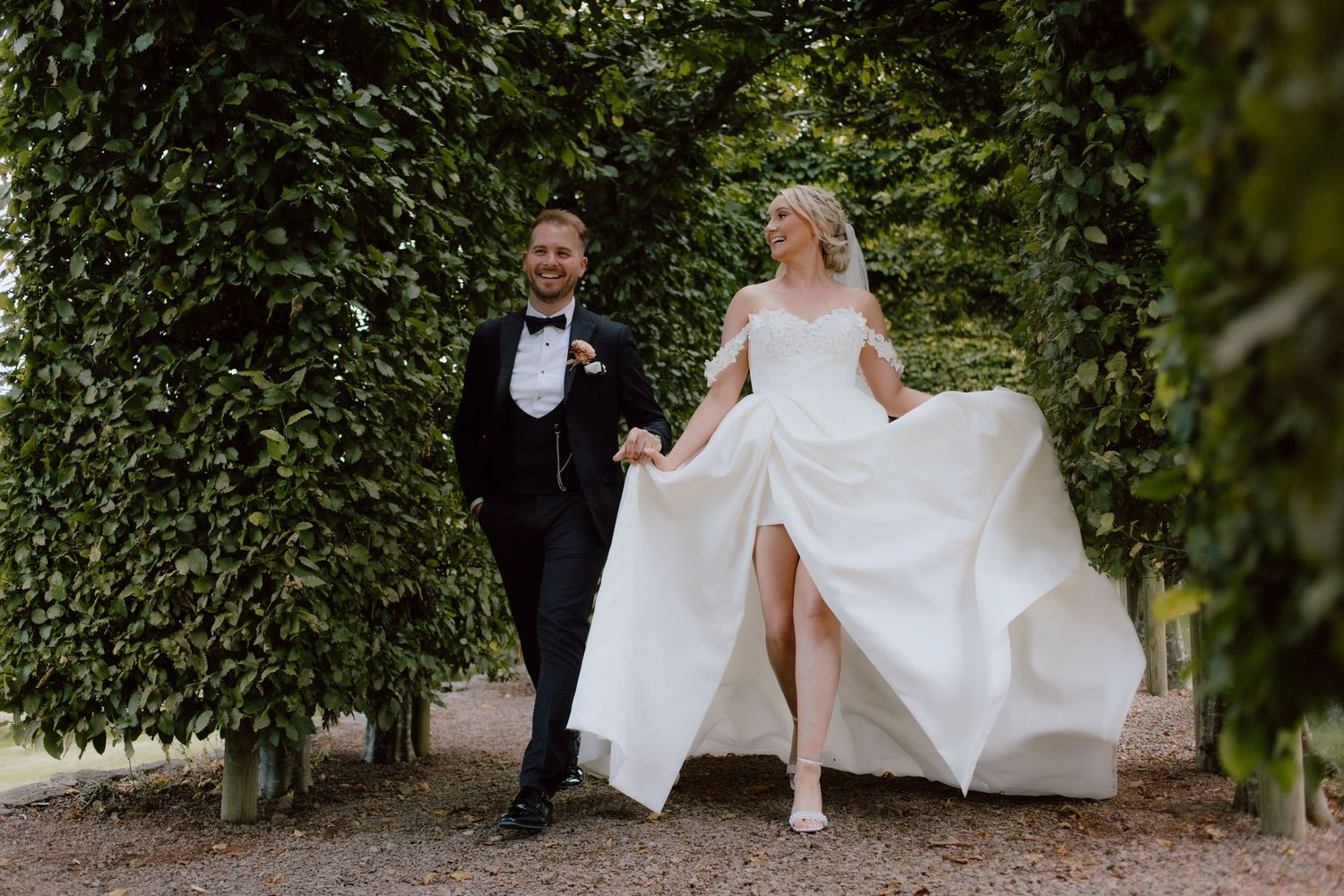 A flowing white wedding dress twirls on a lawn in front of a Tudor-style brick mansion at pauntley court captured by cotswolds photographer.