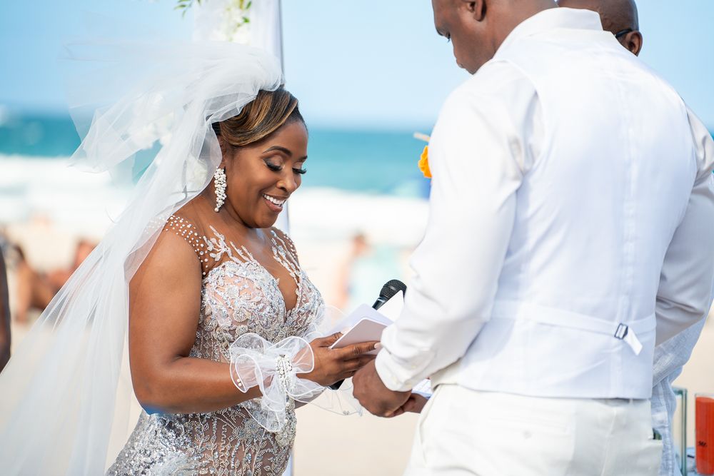 Wedding couple sharing intimate moments during a beachside celebration in white formal attire.