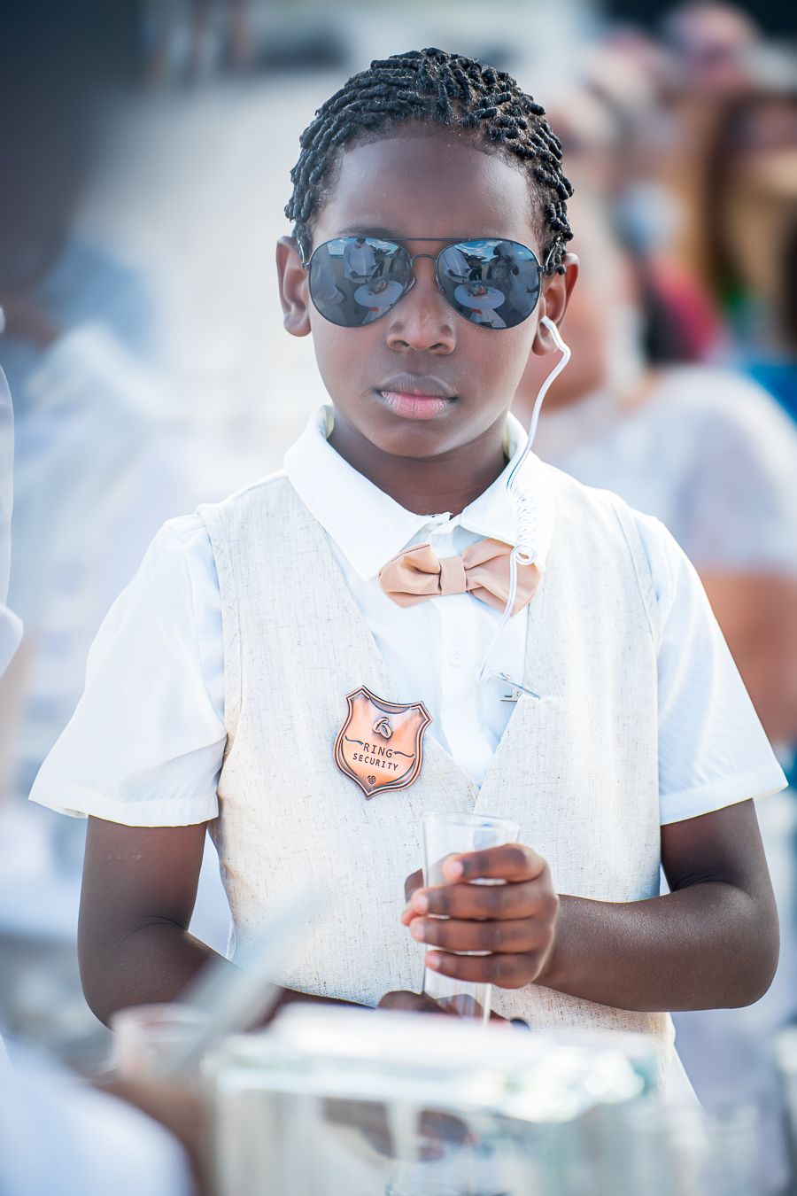 Young musician in white shirt and aviator sunglasses performs in a drumline ensemble during a sunny day.