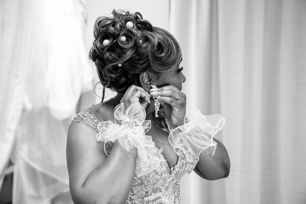 Artistic black and white photo of elegant updo hairstyle with elegant lace wedding dress detailing in soft focus.