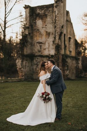 Romantic wedding couple shares intimate moments at sunset near stone ruins.