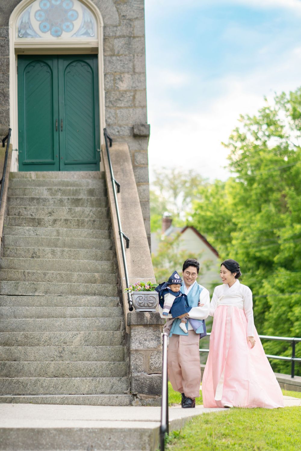 Stone steps leading to green doors of a historic church or building surrounded by lush trees.