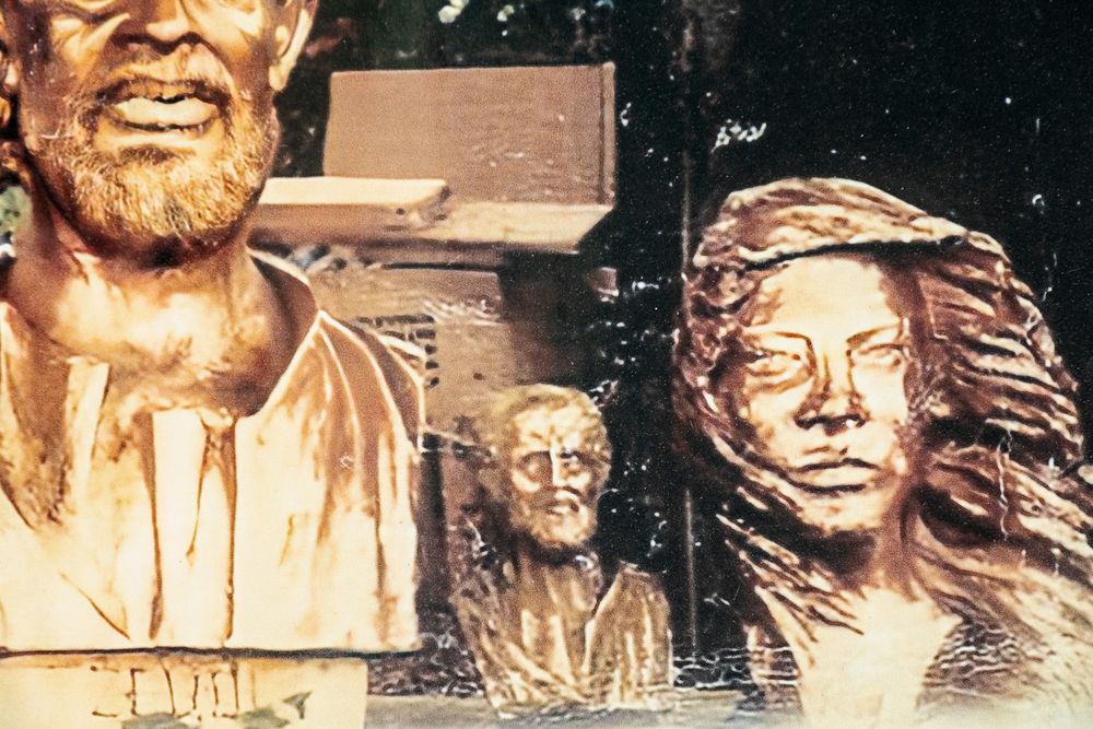 Three sculpted bronze busts displayed together showing different artistic styles and expressions.