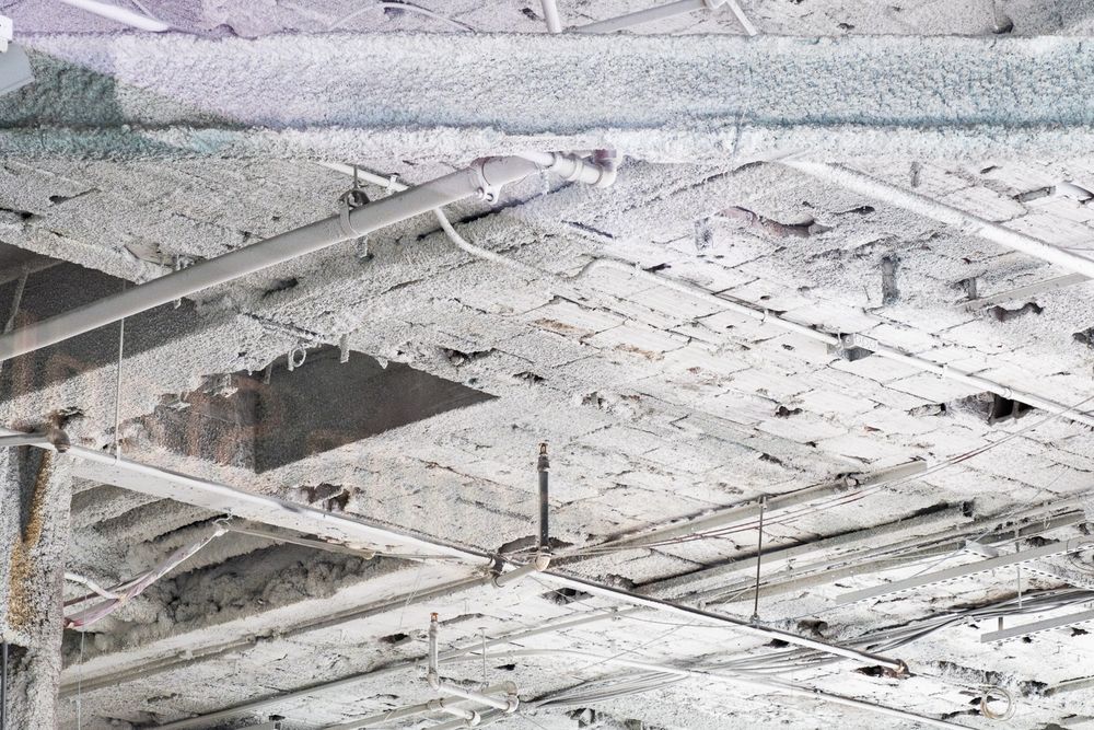 Aerial view of industrial construction site showing concrete foundations and steel support beams covered in snow.