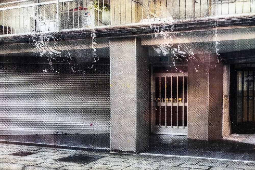 Water cascades from a decorative fountain feature into a still reflecting pool beside a modern building facade.