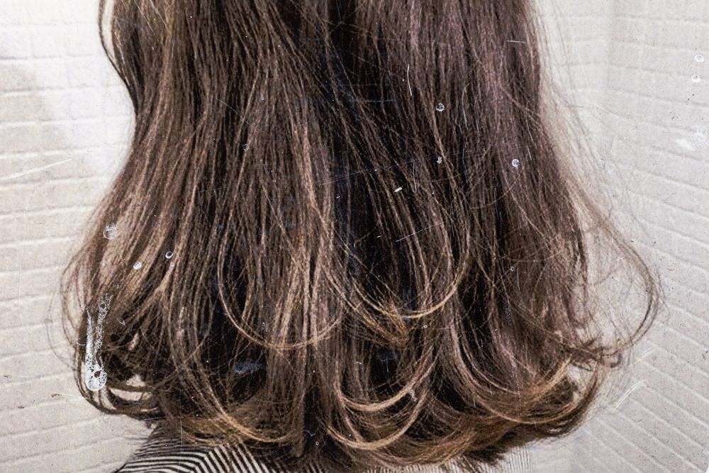 Shoulder-length wavy brown hair with subtle highlights styled with loose curls against a light background.