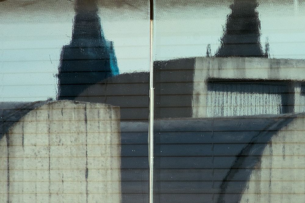 Abstract architectural detail showing industrial cooling towers in muted blue and gray tones with dramatic shadows.