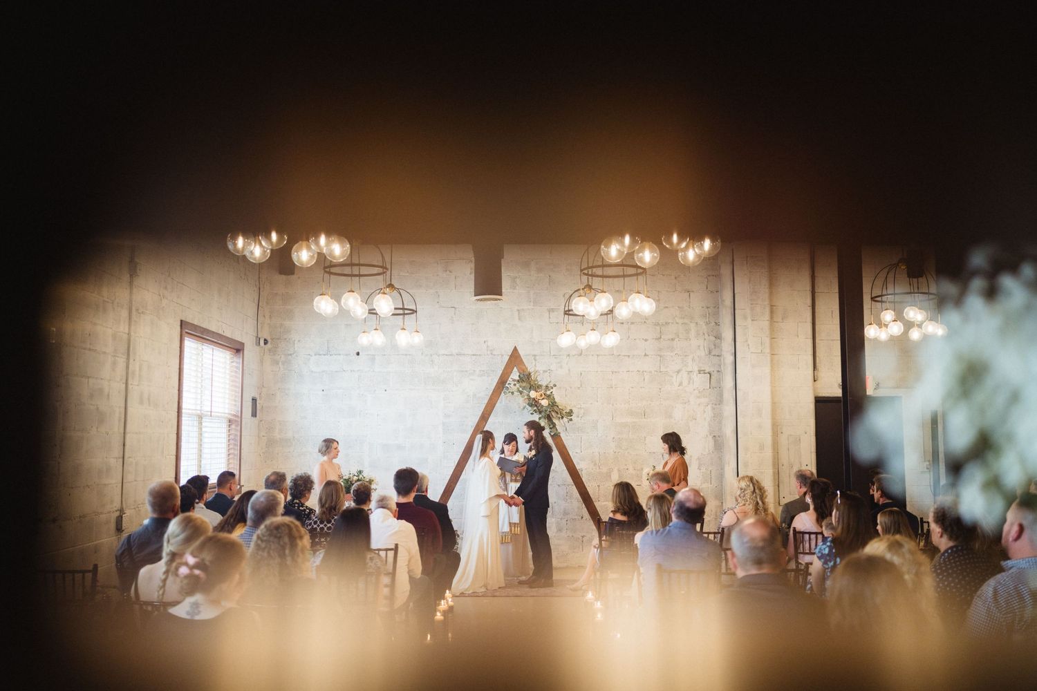 Wedding party members perform synchronized dance moves in an elegant ballroom under crystal chandeliers.