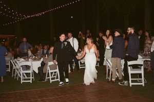 Wedding celebration on outdoor dance floor with guests seated at tables around the perimeter.