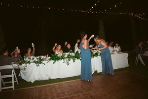 Wedding reception venue decorated with string lights and white chairs at dusk.