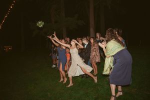 Wedding guests dance outdoors at night under string lights on a grassy lawn.