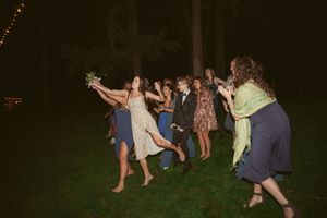 A lively group dancing outdoors at night on a grassy lawn, with party guests enjoying an energetic celebration.
