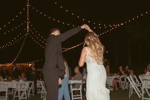 String lights illuminate an outdoor wedding reception space at night.