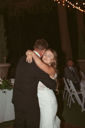 Romantic embrace during a slow dance at an outdoor evening wedding reception.