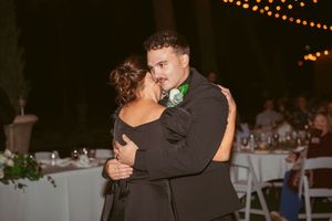 Two silhouettes dance intimately under glowing string lights at an evening celebration.