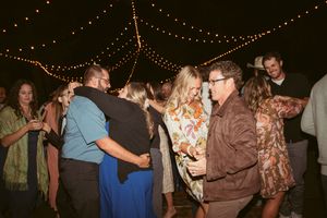 People dancing together under romantic string lights at an outdoor evening celebration party.