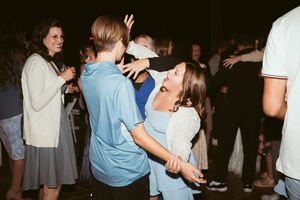 People dancing together at a dimly lit venue during what appears to be a social gathering or party.